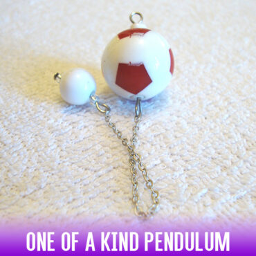 A soccer-ball style red & white acrylic bead dowsing pendulum with an easy-to-use white acrylic bead handle on a silver chain.