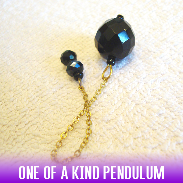 Α dowsing pendulum with black spherical faceted beads on a gold chain makes for a truly striking impression.