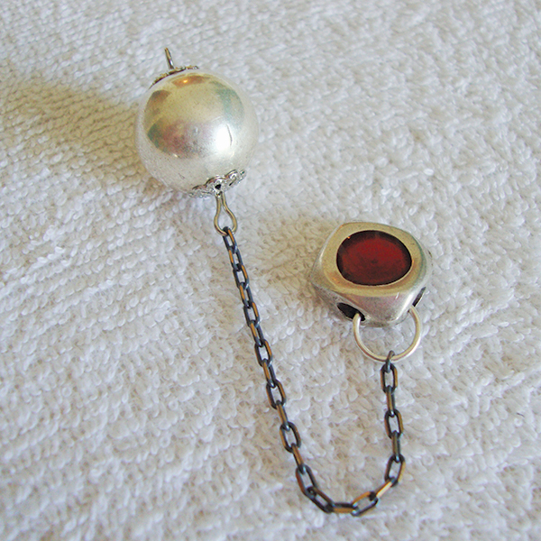 Silver metallic ball pendulum with a red button-like metallic clasp