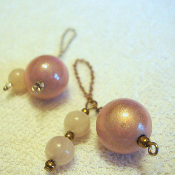 A soft pink, light-weight iridescent round acrylic ball pendulum with either gold or silver chain