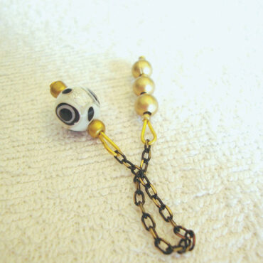 A black, white & gold acrylic bead dowsing pendulum with a 3 small bead handle and an antique black & gold chain