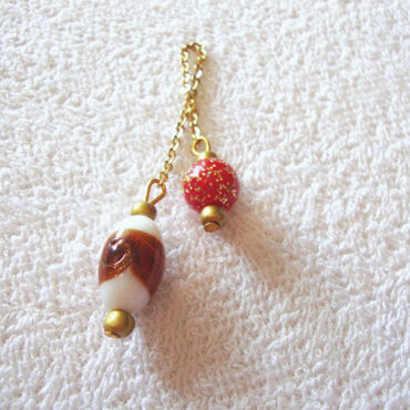 An artisan handcrafted Murano glass dowsing pendulum with copper & gold details and a red sparkle bead handle with a gold chain
