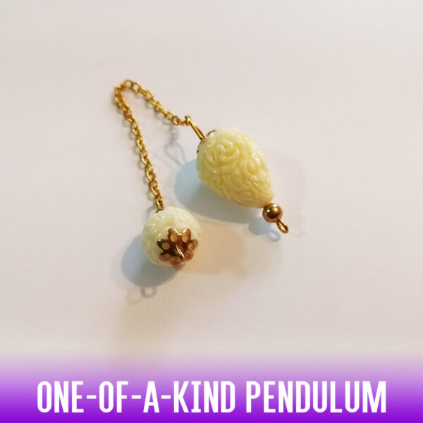 A one-of-a-kind small teardrop dowsing pendulum made of off-white hand-carved faux coral beads and a gold chain