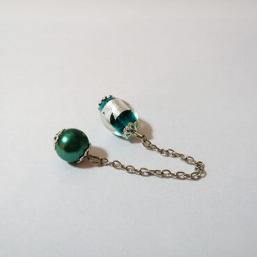 A dowsing pendulum made with a deep green and silver foil luminous Murano lampwork oval bead and silver end caps. A silver chain and a deep green acrylic sphere bead, complete the look.