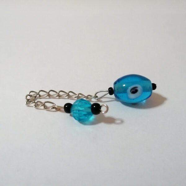 An artisan dowsing pendulum of handcrafted light blue oval glass lampwork bead with the classic "away with evil-eye" and small black bead details. A silver chain and a light blue glass handle complete the look.