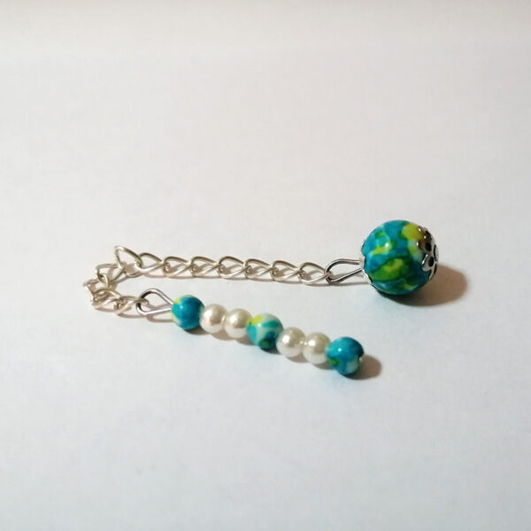 A dowsing pendulum of petite turquoise and yellow green colored stone beads with a long handle of 7 petite colored stone and faux pearl beads with a silver chain.