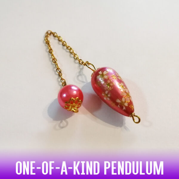 A one-of-a-kind 21mm teardrop dowsing pendulum made with a flower printed pattern on metallic colored hot pink acrylic bead with golden end caps. A color-matched acrylic bead at the handle and silver chain complete this rich and feminine look.